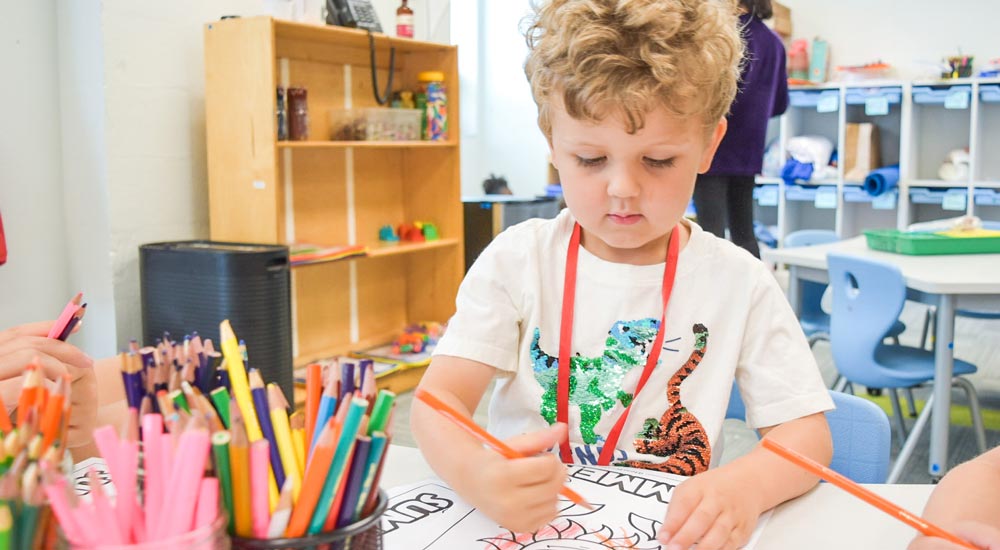 Young boy drawing with colored pencils