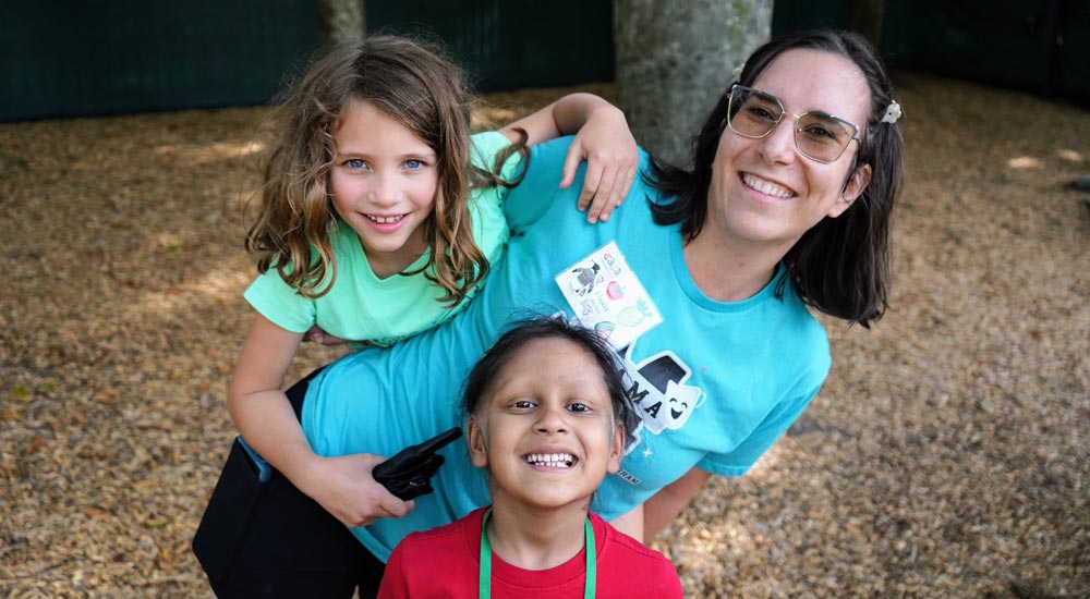 Camp counselor with two campers, all smiling